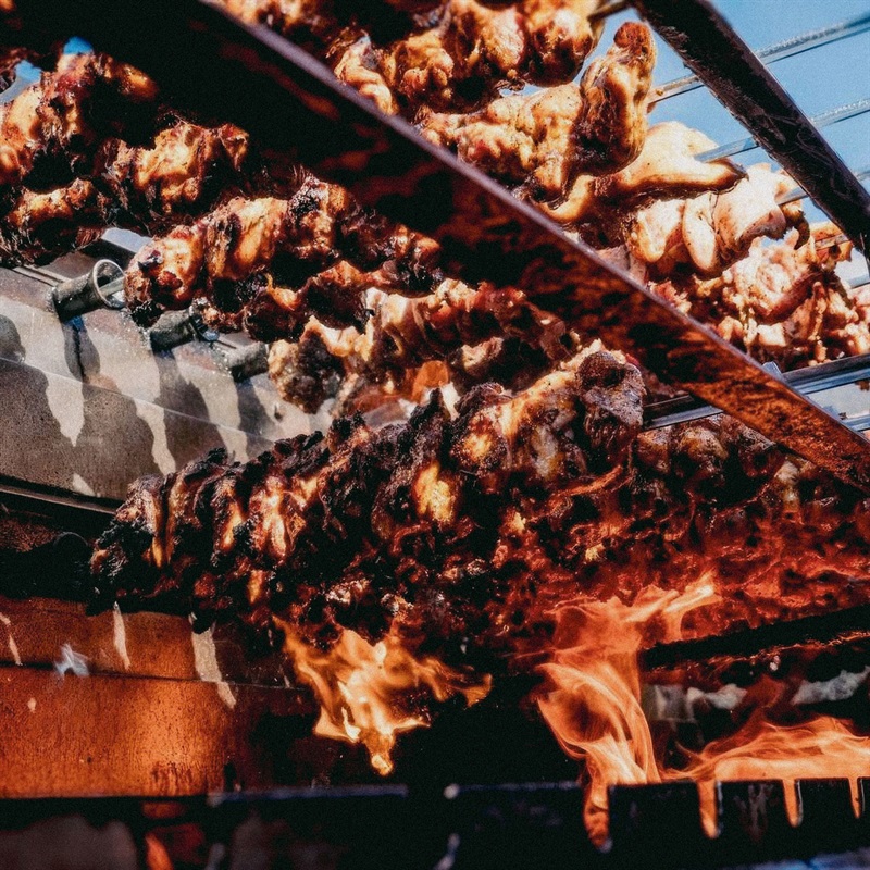 Meat being flame grilled on rotisseries - Brazzo Boys Barbeque
